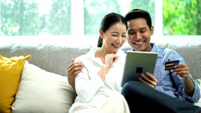 4k微笑的女人使用数字平板电脑，而开朗的男人在网上购物时拿着Visa信用卡