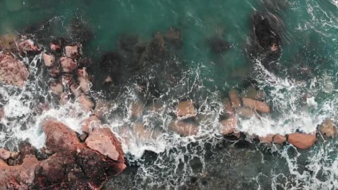 大浪撞击海石的特写鸟瞰图。大风天的海浪