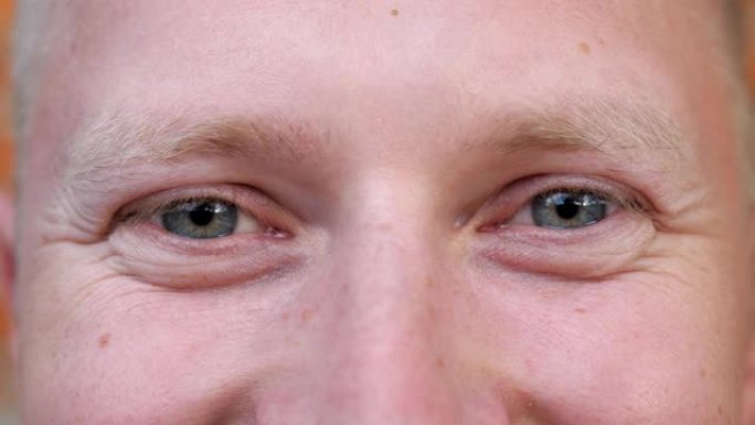 细节视图男人的蓝眼睛凝视着幸福的眼睛。男性脸的肖像以积极的情绪看着镜头。微笑的年轻人的面部表情。特写