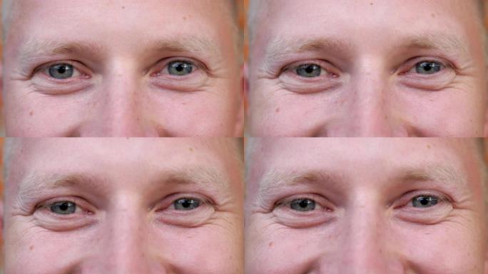 细节视图男人的蓝眼睛凝视着幸福的眼睛。男性脸的肖像以积极的情绪看着镜头。微笑的年轻人的面部表情。特写