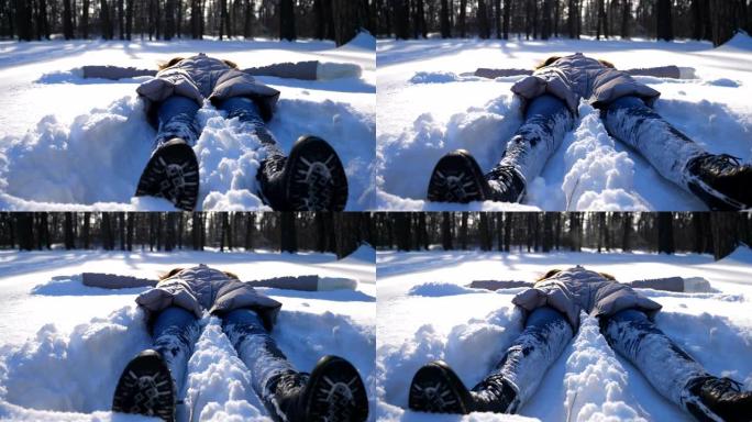穿着冬装的年轻女孩躺在白雪皑皑的草地上，做天使。快乐的女人在雪地里玩耍，享受冬天的时光。开朗的女士在