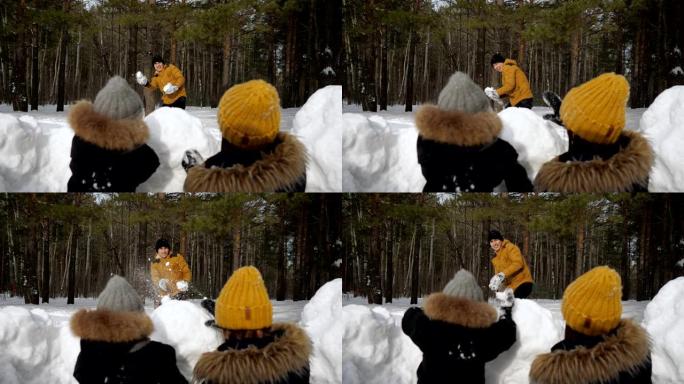 男人和他的家人，妻子和小儿子躲在雪墙前玩雪球。