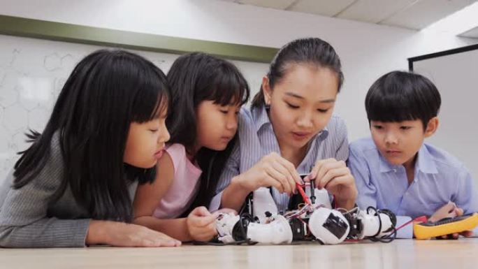 机器人班的学生和老师。顾问向学生解释她的机器人项目。