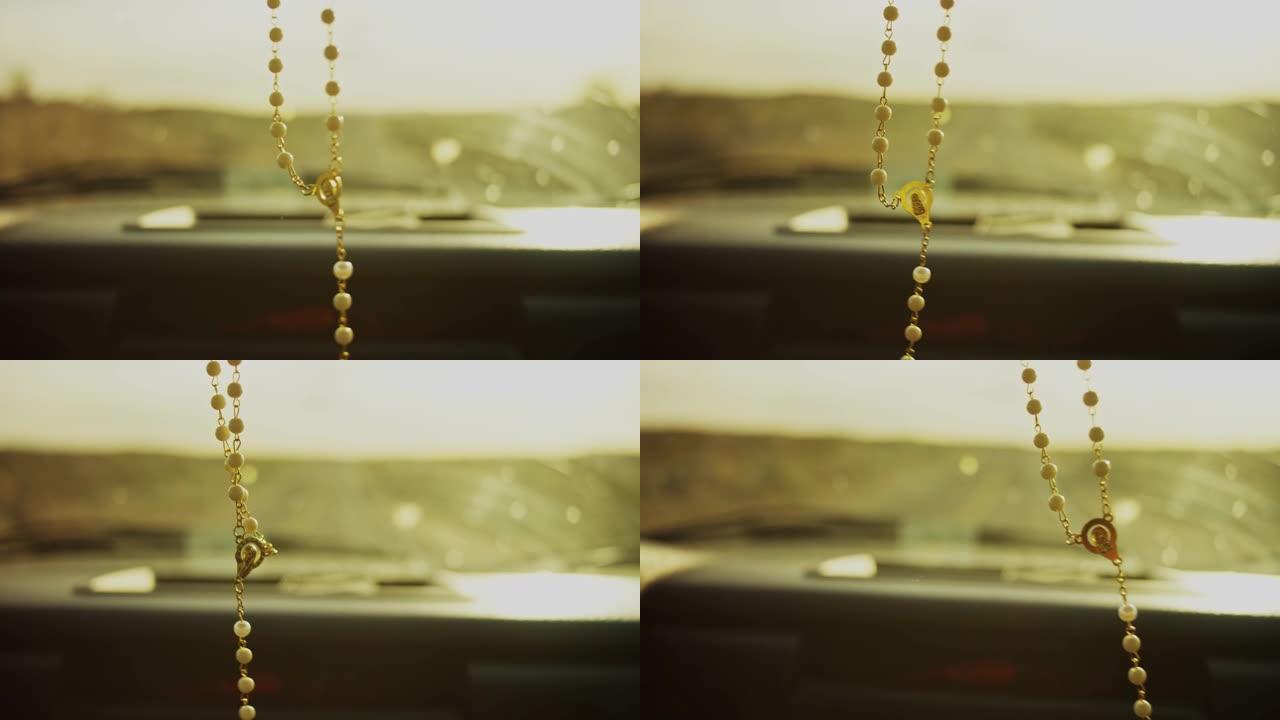 在沙漠中，当夕阳西下时，玫瑰十字在汽车后视镜上摆动。
