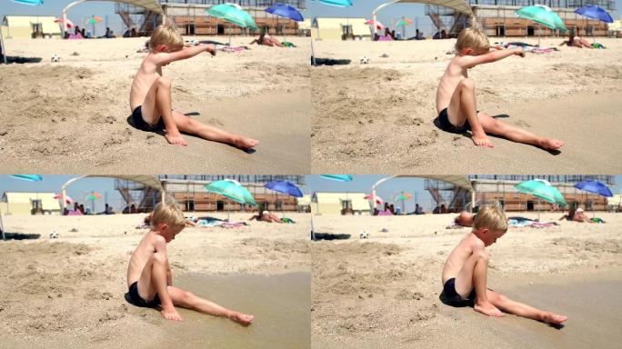 夏天，小可爱男孩坐在海边的沙滩上晒太阳。