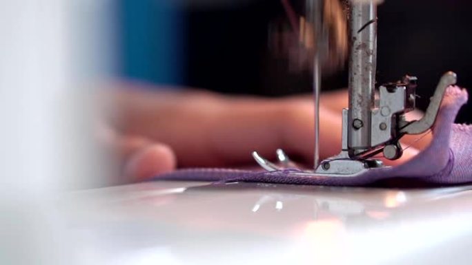 女人用电动缝纫机缝制衣服。