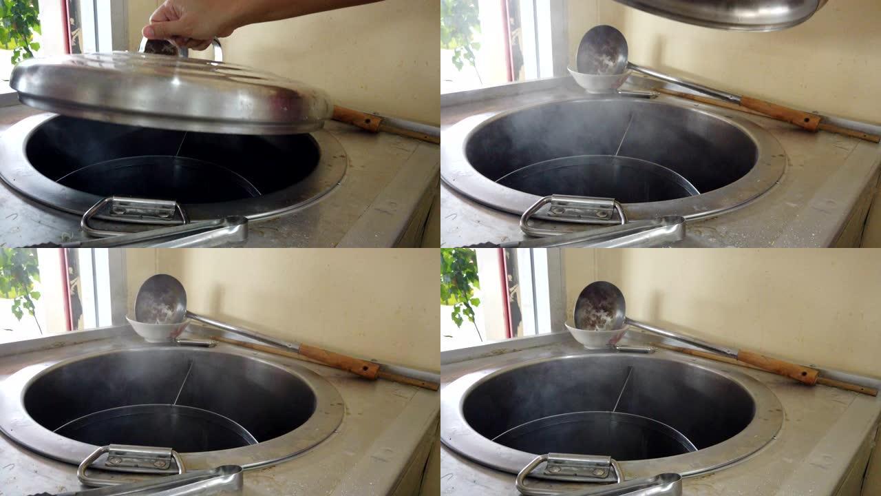 女人用手打开煮沸和热腾腾的面条锅。