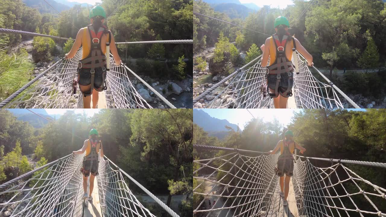 女人享受着绳索桥穿越峡谷河的极端冒险