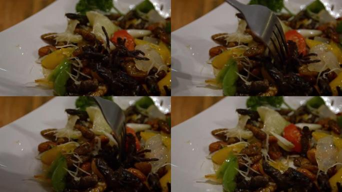 慢动作的人在一家亚洲餐厅吃一盘虫子作为晚餐