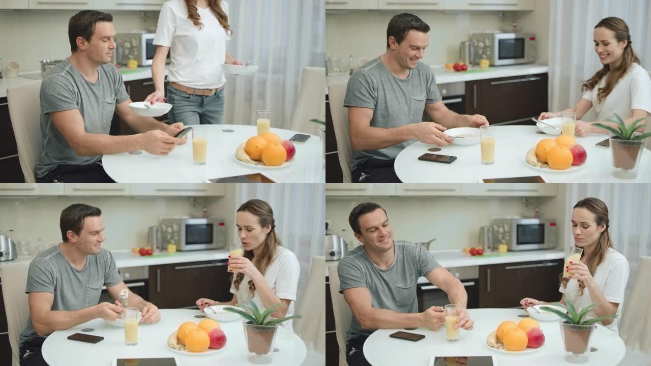 快乐的夫妇在客厅健康早餐时喝橙汁。