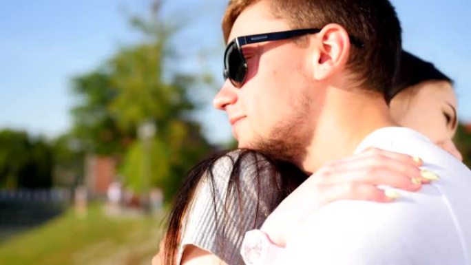 年轻的微笑夫妇在阳光明媚的公园拥抱，糖果花时期，真实的感受。一起快乐。特写镜头。