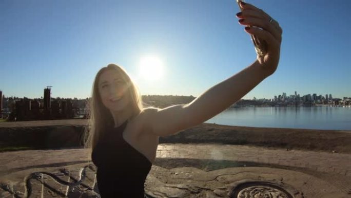 年轻的成年女性社交媒体名人用她的智能手机相机摆姿势自拍，展示她时尚的生活方式