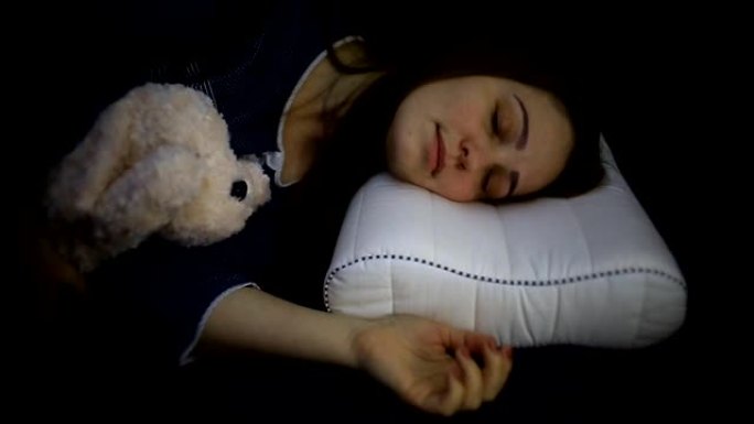 一名年轻女子穿着蓝色衬衫的毛绒玩具睡在矫形枕头上