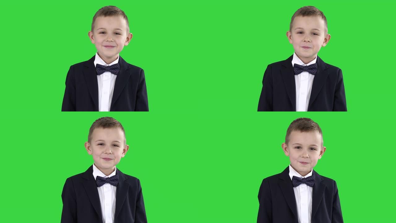 微笑的小男孩穿着正式的衣服站在绿色屏幕上，色度键