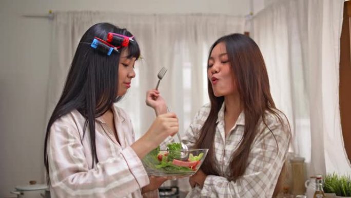 年轻的亚洲女性早餐准备沙拉。家庭概念。
