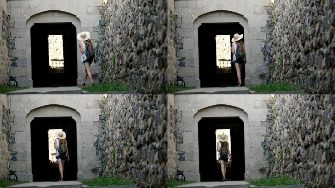 一个戴着帽子背着背包的年轻女子走进了一座古老建筑的拱门