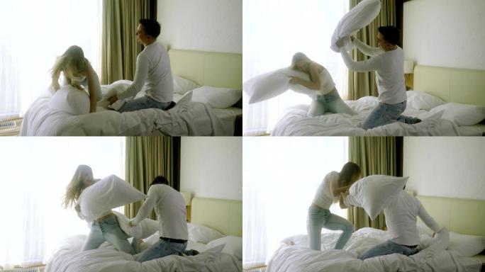 快乐的男人，女人玩得开心，在豪华卧室的床上用枕头打架。4K