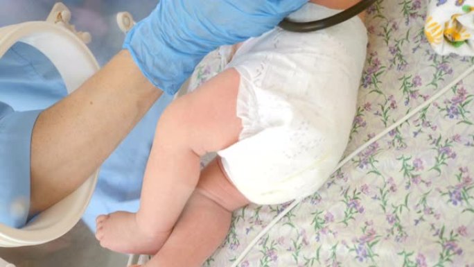 妇产医院的概念。拯救婴儿的生命。在医生监护下的保育箱中的早产儿。特写镜头，护士的手在蓝色手套拿着奶瓶