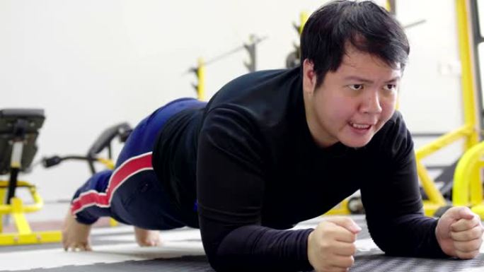 亚洲男子试图在健身馆用哑铃锻炼，健康的生活方式，减肥欲望