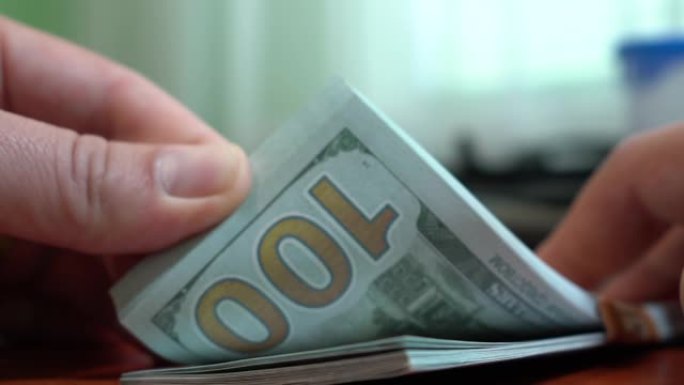 手指在一叠钞票中分类。一叠100美元的钞票。特写。假币。