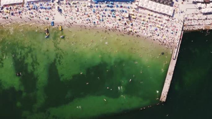 晴天夏日海滩生活的空中延时俯视图。很多人在水中游泳