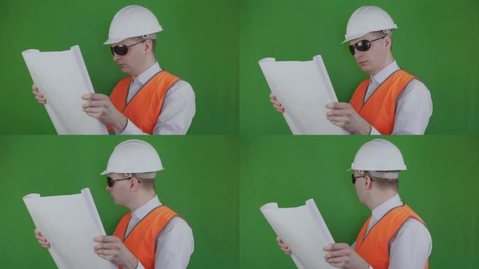 Builder打开并查看有关新建筑的技术图纸。Chromakey。工程师和房地产市场。穿着白色头盔和