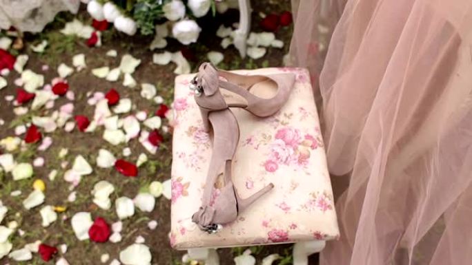 为新娘在长椅上放鲜花的粉红色结婚鞋的特写镜头。