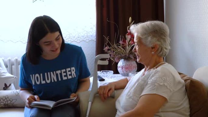 年轻志愿者在家为高级女性阅读的书