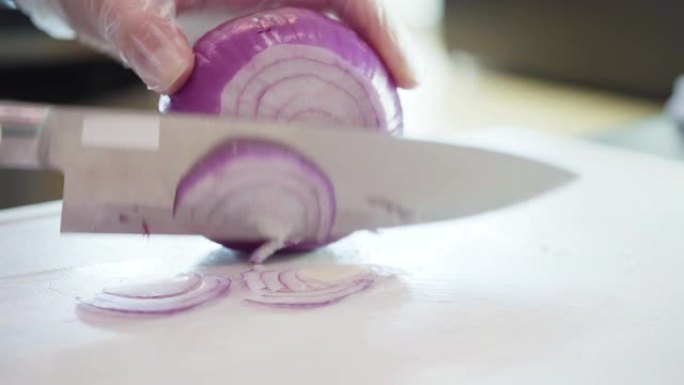 在白色砧板上切紫色洋葱。