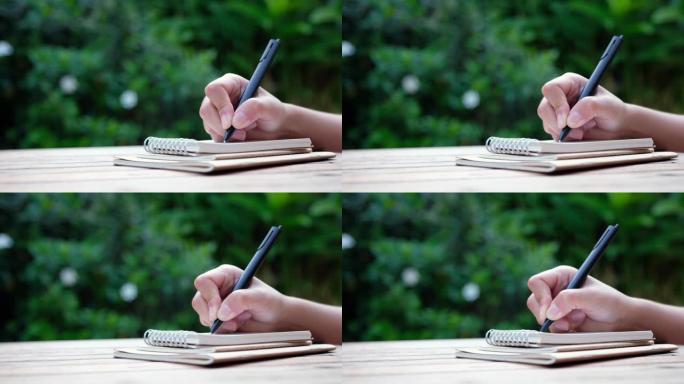 一个女人在木桌上的空白笔记本上写字