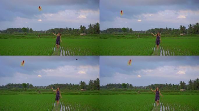 慢动作拍摄一名年轻女子的风筝穿过美丽的稻田