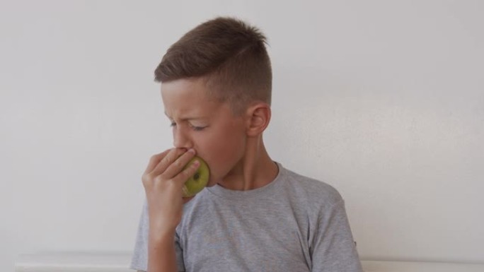 特写肖像男孩吃美味的青苹果，看着相机