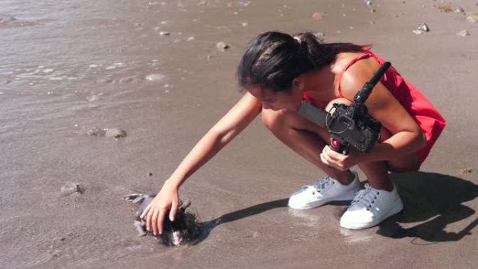 一名女性视频记录器在拍摄视频时在海边发现了一条死鱼。