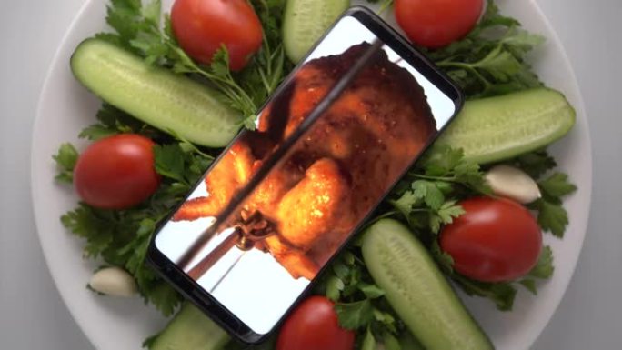 手机在盘子里，屏幕上有烤肉店整鸡。