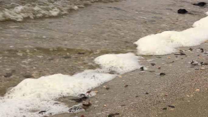 波浪在河岸上滚动，用泡沫敲打石头