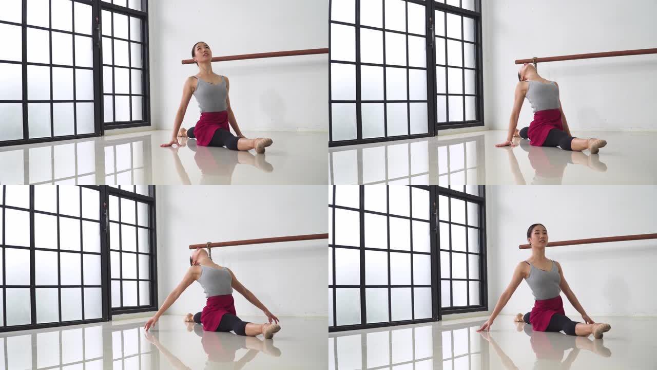 年轻的芭蕾舞女坐着时伸展身体