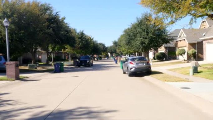 前视图驾车穿过郊区房地产街的住宅，路边有垃圾和垃圾回收箱