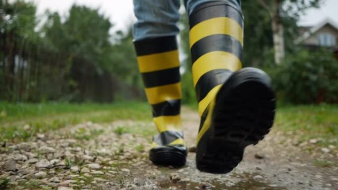 一名男子穿着黑色和黄色的条纹橡胶靴沿着跑道行走