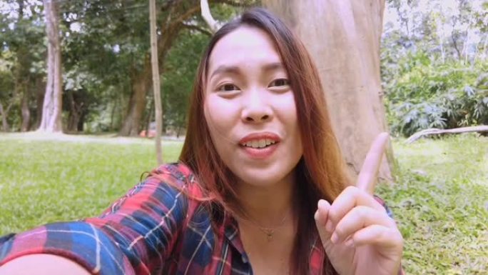 亚洲妇女在公园里用手机与聋哑朋友聊天，拿着智能手机进行视频聊天。