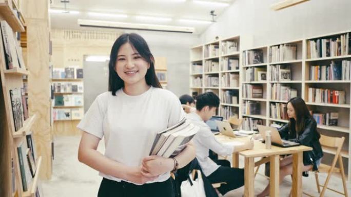 一位可爱的年轻亚洲女学生站在图书馆的肖像