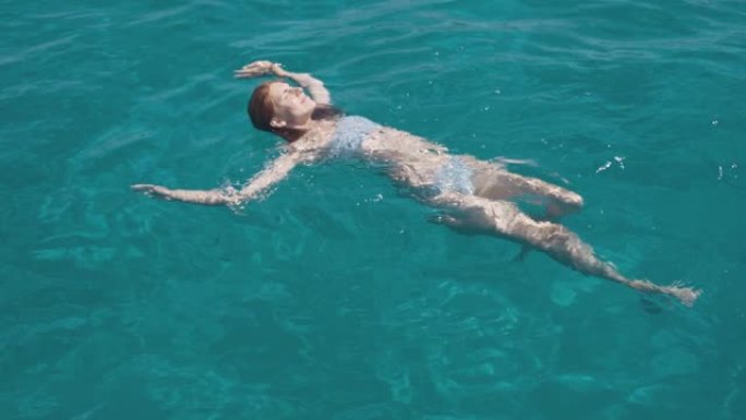 美丽的年轻女子在豪华雅赫附近的福门特拉或伊维萨群岛附近的清澈蓝色水中游泳