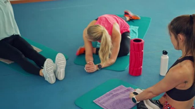三个女人在健身房的地垫上伸展