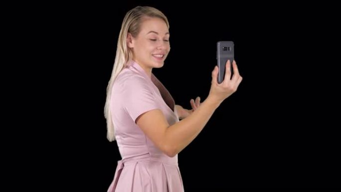 穿着粉红色连衣裙的女性用她的智能手机阿尔法频道进行视频通话