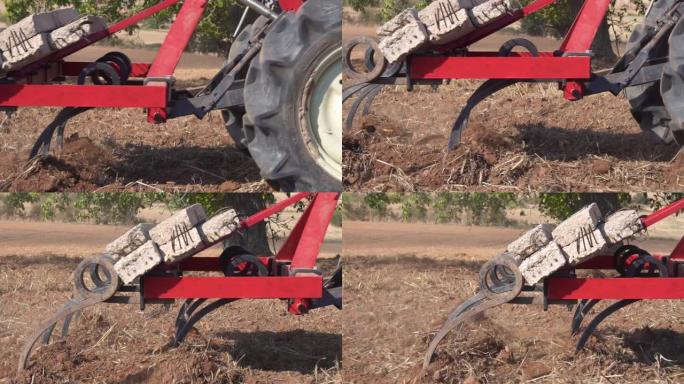红色拖拉机与犁犁田间土壤在慢动作中近距离观察。