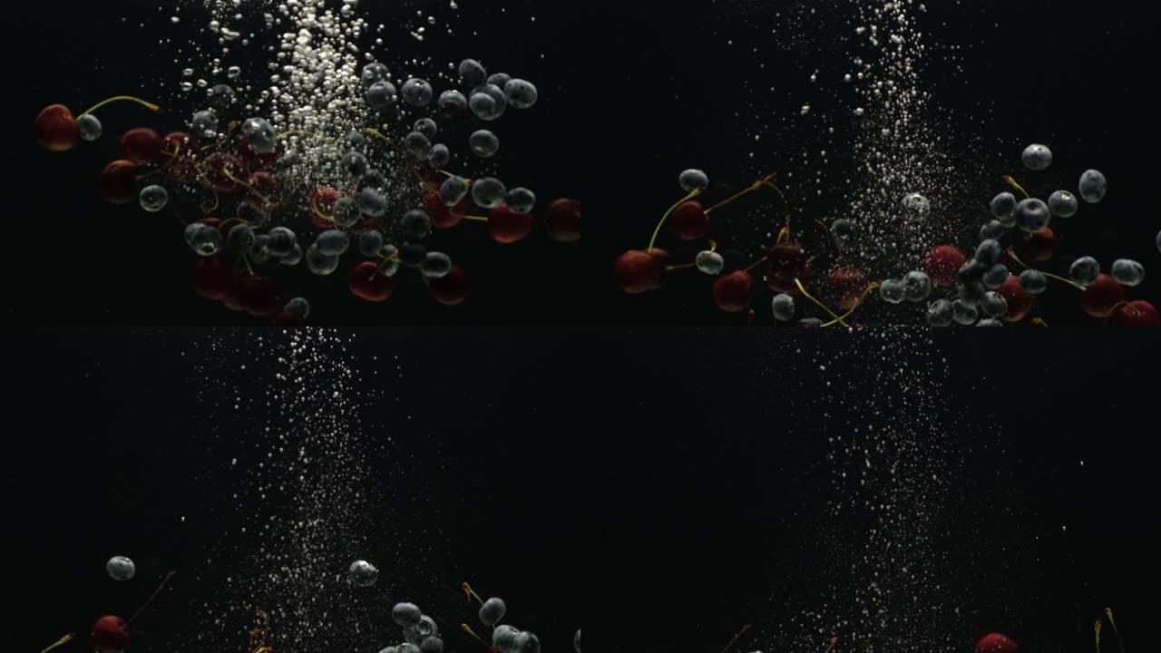 慢动作视频，樱桃和蓝莓在黑色背景上掉入水中
