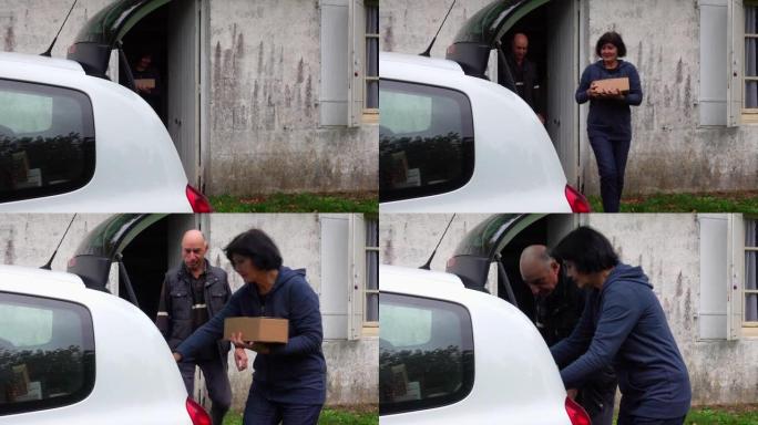 一对夫妇离开房子，一个女人在汽车后备箱里放了一个纸箱