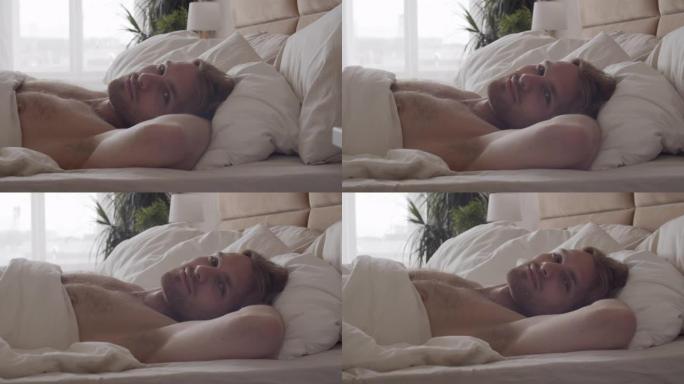 迷人的男人躺在床上，对着镜头微笑