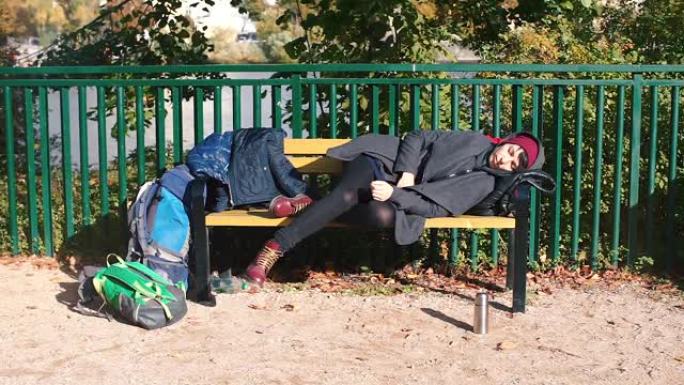 无家可归的漂亮女孩躺在长凳上睡觉