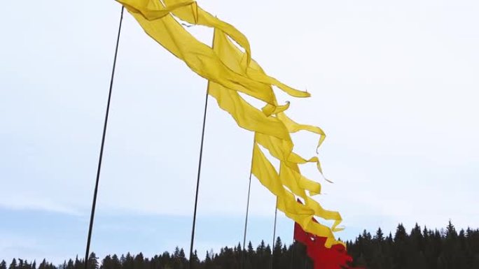 夏季节日期间，天空背景旗杆上飘扬亮黄色和红色横幅