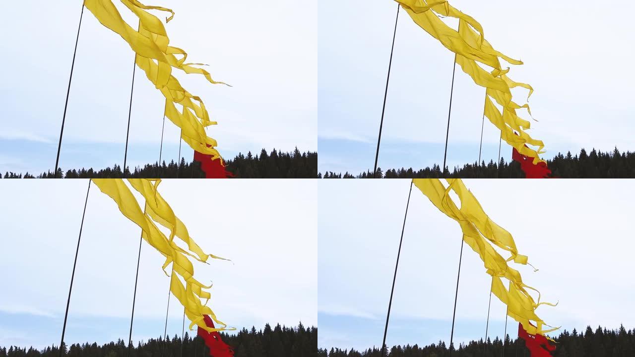 夏季节日期间，天空背景旗杆上飘扬亮黄色和红色横幅